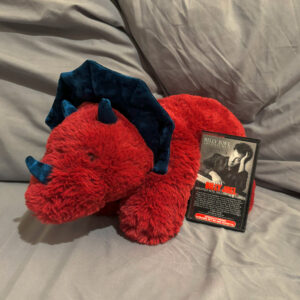 long red triceratops stuffed animal with Billy Joel's Greatest Hits cassette tape