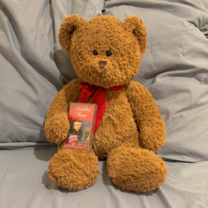 large brown teddy bear in a red ribbon with Holiday Music cassette tape